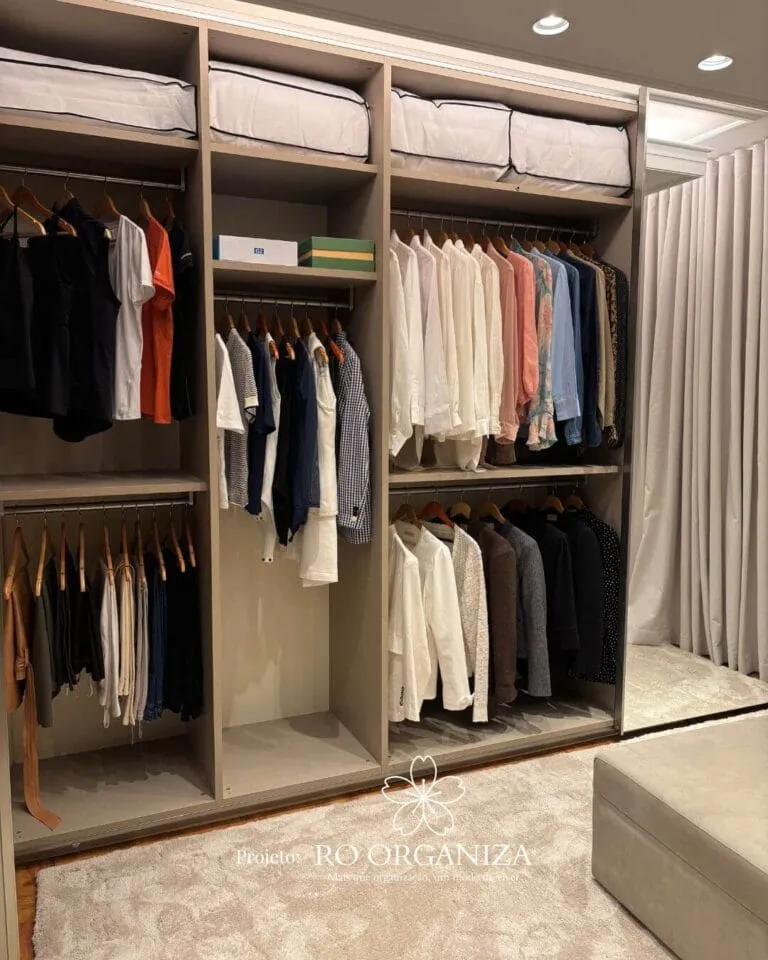 Closet de casal organizado pela Ro Organiza, com roupas penduradas por tipo e cor e caixas nas prateleiras de cima